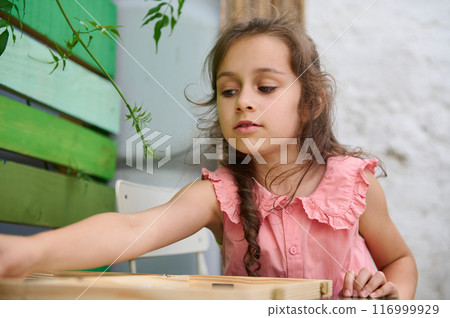 Young girl in pink dress playing with wooden blocks indoors Young girl in pink dress playing with wooden blocks indoors 116999929
