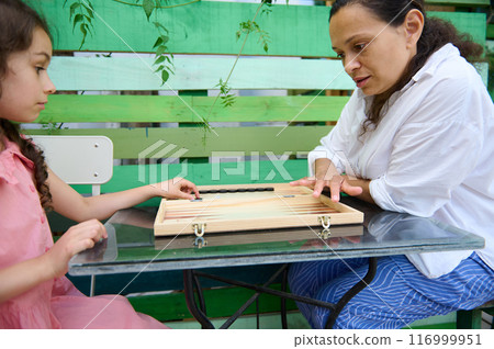 Mother and daughter bonding over board game outdoors Mother and daughter bonding over board game outdoors 116999951