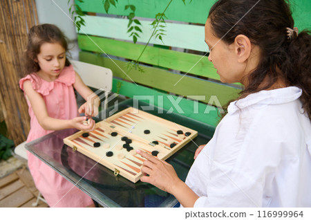 Mother and daughter playing backgammon board game together outdoors on a sunny day Mother and daughter playing backgammon board game together outdoors on a sunny day 116999964