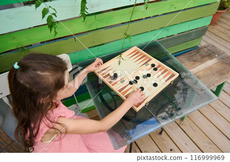 Young girl playing backgammon outdoors on a colorful wooden table Young girl playing backgammon outdoors on a colorful wooden table 116999969