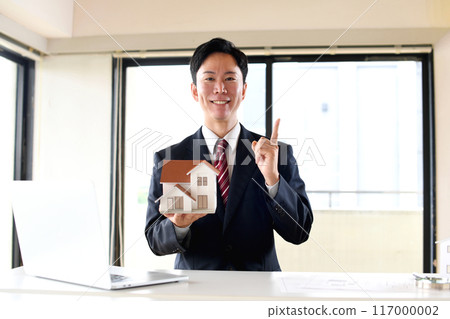 穿著西裝的男性辦公室職員拿著房屋模型 穿著西裝的男性辦公室職員拿著房屋模型 117000002
