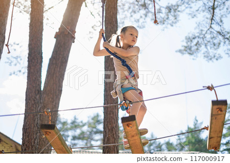 A brave strong girl in hiking gear walks the track on a suspension bridge at a height A brave strong girl in hiking gear walks the track on a suspension bridge at a height 117000917