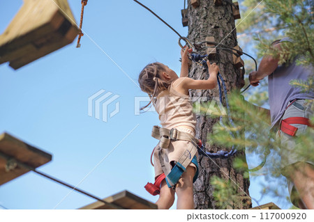 The child adjusts the safety carabiner to pass the rope route at height The child adjusts the safety carabiner to pass the rope route at height 117000920