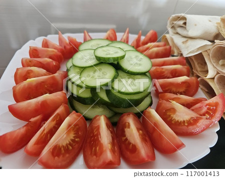 A plate of chopped tomatoes and cucumbers and a plate of pita bread with cheese. Preparing for a picnic in nature 117001413