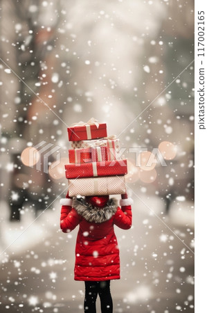 Woman Carrying Gift Boxes in Snowy Urban Setting During Winter Holiday Season 117002165