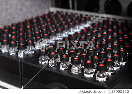 Glass vials with black caps are in racks of HPLC system.  117002560