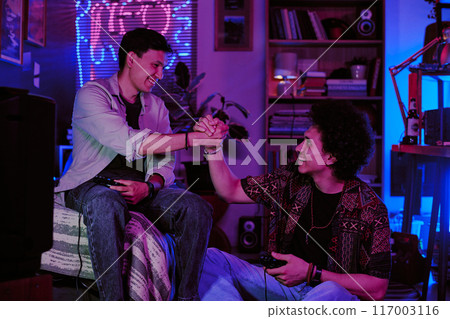 Two guys giving bro handshake after game challenge in retro dorm room Two guys giving bro handshake after game challenge in retro dorm room 117003116