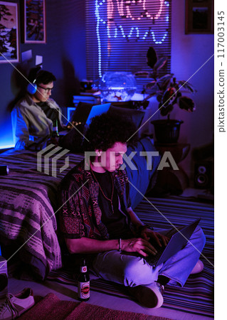 Student chilling in neon dorm room, they playing computer game, drinking beer and listening to music 117003145