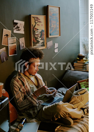Tired programmer eating noodles to restore energy after full remote work day, he sitting on bed surrounded by laptops with codes on their screens Tired programmer eating noodles to restore energy after full remote work day, he sitting on bed surrounded by laptops with codes on their screens 117003149