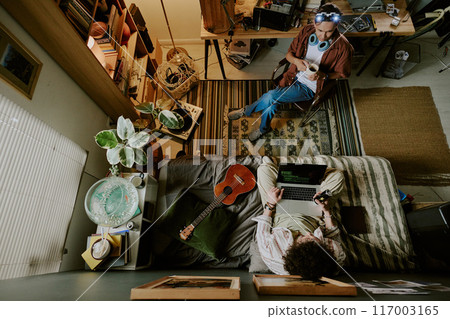 Top view shot of two roomies having break during remote work day, they talking to each other and chilling Top view shot of two roomies having break during remote work day, they talking to each other and chilling 117003165