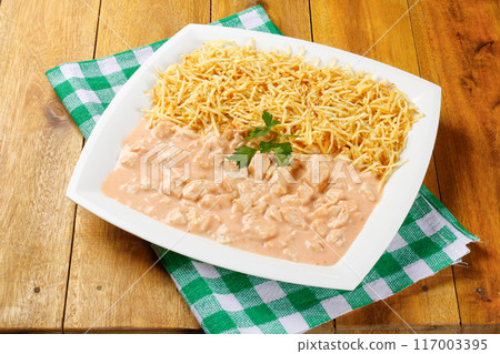 Homemade chicken stroganoff in ceramic plate on red checkered tablecloth 117003395