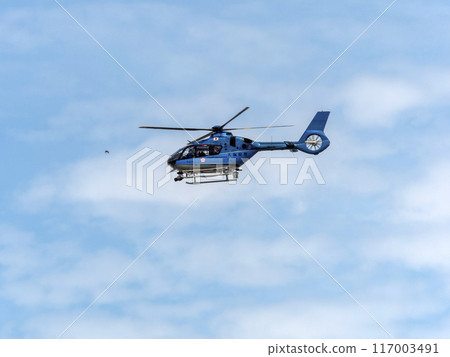 A helicopter of the Osaka Prefectural Police Aviation Unit flying in the midsummer sky 117003491