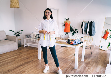 Smiling casual dressmaker in studio 117003649