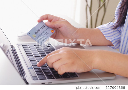 A woman entering credit card information into a computer A woman entering credit card information into a computer 117004866