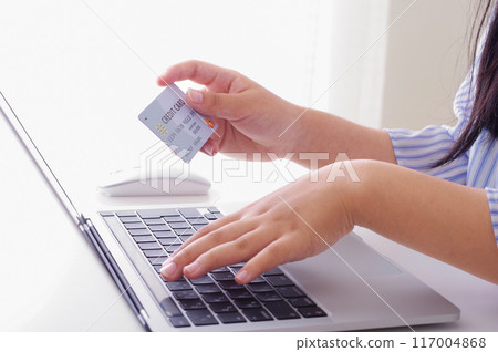 A woman entering credit card information into a computer A woman entering credit card information into a computer 117004868