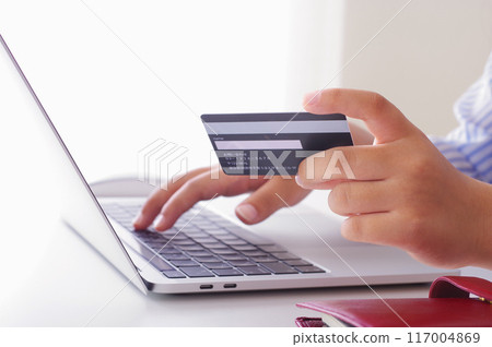 A woman entering credit card information into a computer A woman entering credit card information into a computer 117004869