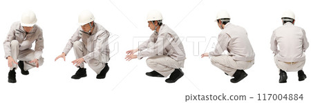 Full-body cutout of a man wearing helmet and work clothes in the factory or construction industry squatting 117004884