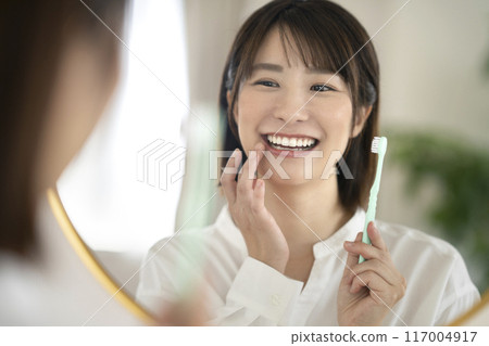 一位老婦一邊照鏡子一邊刷牙 117004917
