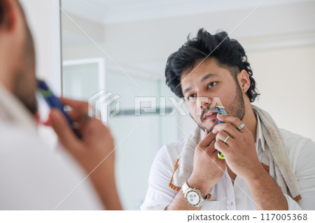 Man shaving while looking in the mirror 117005368