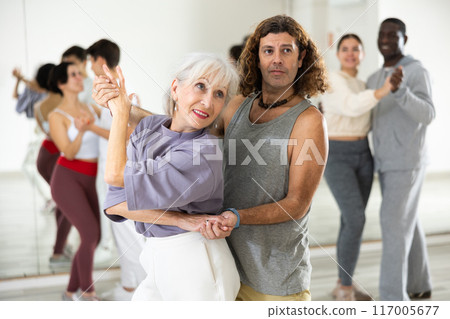 Positive adult man and smiling aged woman dancing in pair Positive adult man and smiling aged woman dancing in pair 117005677