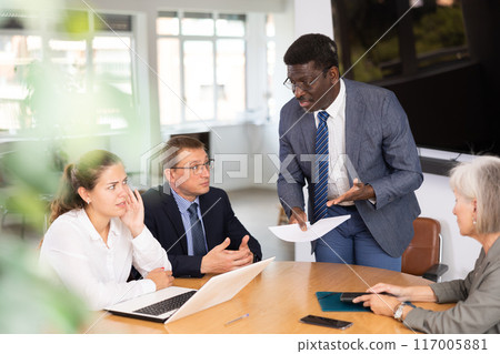 Angry middle-aged man shouting at his business partners sitting around table 117005881