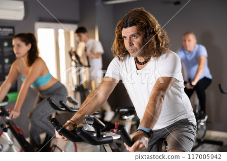 Man doing cardio training on stationary bike in gym 117005942