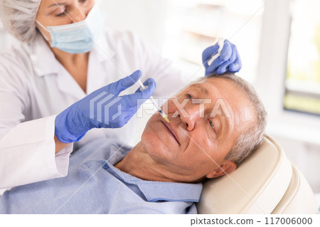 Old man having face care by means of injection in aesthetic clinic Old man having face care by means of injection in aesthetic clinic 117006000