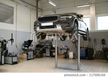 Car on hydraulic lift in modern auto repair shop Car on hydraulic lift in modern auto repair shop 117006160