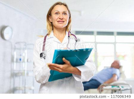 Adult woman doctor making notes in medical office 117006349