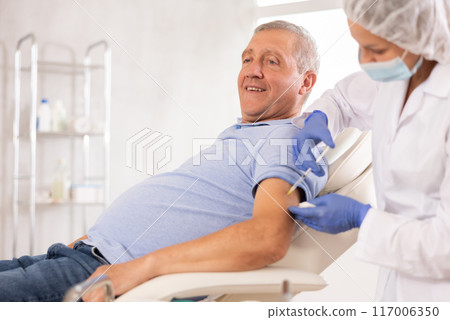 Woman doctor makes injection in arm of man Woman doctor makes injection in arm of man 117006350