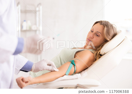 Man doctor makes an injection in arm of woman 117006388