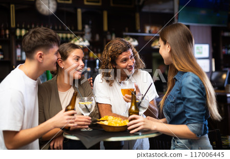 Friends drinking beer and having conversation in bar 117006445