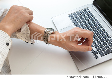 A man rolling up his sleeves in front of a computer in the office 117007220