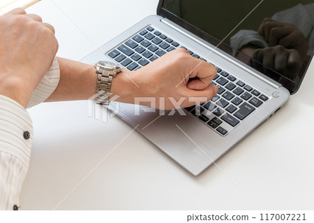 A man rolling up his sleeves at his desk in the office 117007221