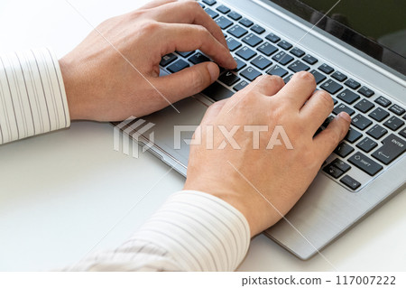 man typing on laptop keyboard 117007222