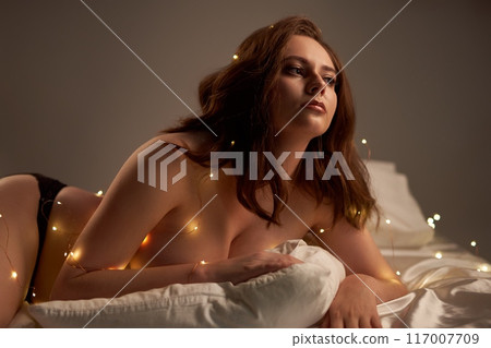 Alluring young woman lying on bed and waiting for Christmas 117007709