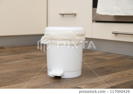 Trash can with bag on wooden floor on light background Trash can with bag on wooden floor on light background 117008426
