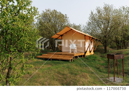 Cozy open glamping tents with light inside in summer camp. Camping tent for holiday and vacation Cozy open glamping tents with light inside in summer camp. Camping tent for holiday and vacation 117008730