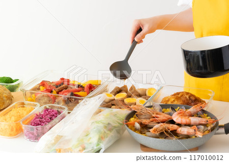 A woman in an apron arranging prepared food 117010012