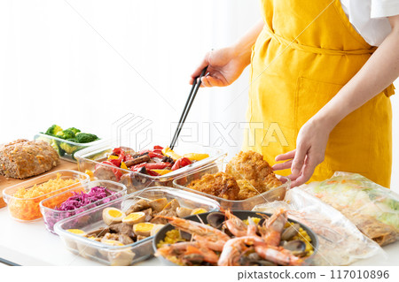 A woman in an apron serving prepared food 117010896