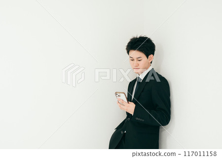 A handsome businessman in his twenties operating a smartphone A handsome businessman in his twenties operating a smartphone 117011158
