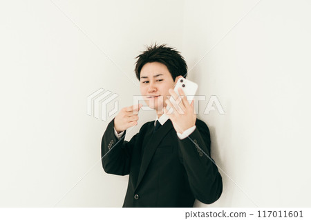 A man in his 20s pointing at his smartphone 117011601