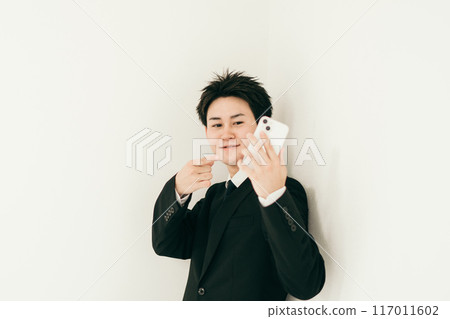 A man in his 20s pointing at his smartphone A man in his 20s pointing at his smartphone 117011602