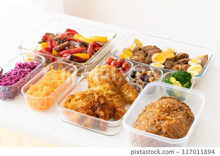 Prepared meals packed in glass storage containers lined up on a table by the window 117011894