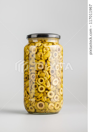 Sliced pickled green olives in brine in jar on gray background. Sliced pickled green olives in brine in jar on gray background. 117011967