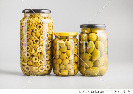Pickled green olives in brine in jar on gray background. Pickled green olives in brine in jar on gray background. 117011969