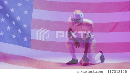 Image of african american american football player kneeling with ball and flag of usa 117012126