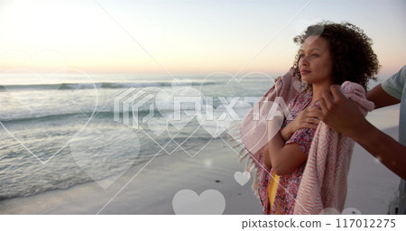 Image of hearts moving over diverse couple in love on beach in summer Image of hearts moving over diverse couple in love on beach in summer 117012275