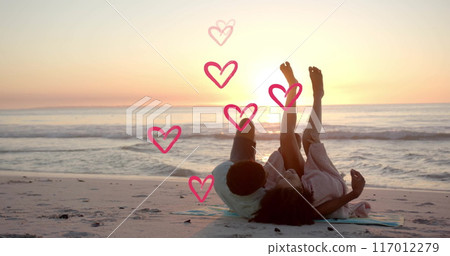 Image of hearts moving over diverse couple in love embracing on beach in summer Image of hearts moving over diverse couple in love embracing on beach in summer 117012279