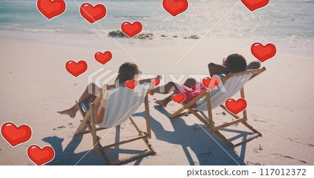 Image of hearts moving over diverse couple in love in deckchairs on beach in summer Image of hearts moving over diverse couple in love in deckchairs on beach in summer 117012372